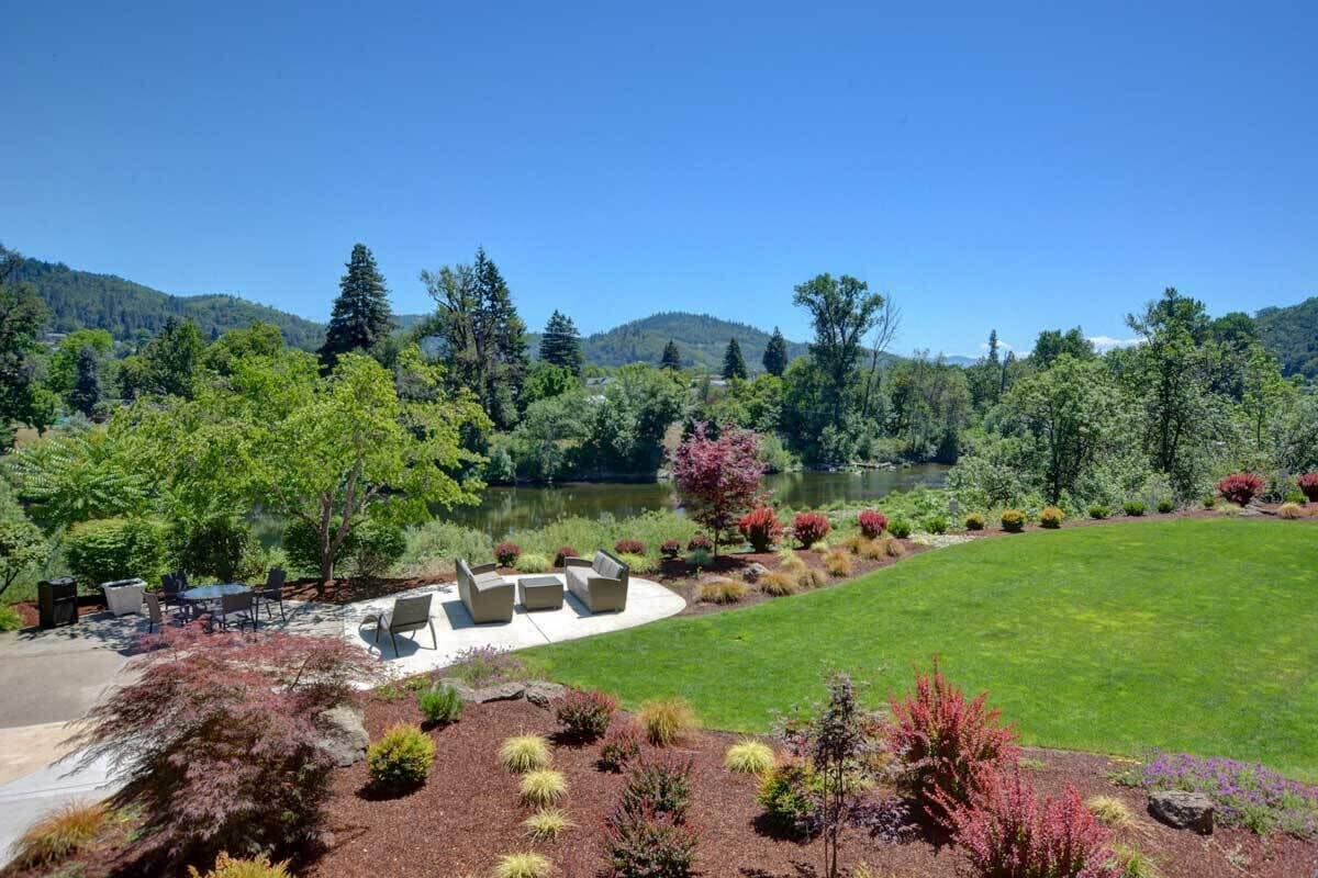 Un jardin aménagé avec une pelouse, un espace détente et une vue sur un lac.