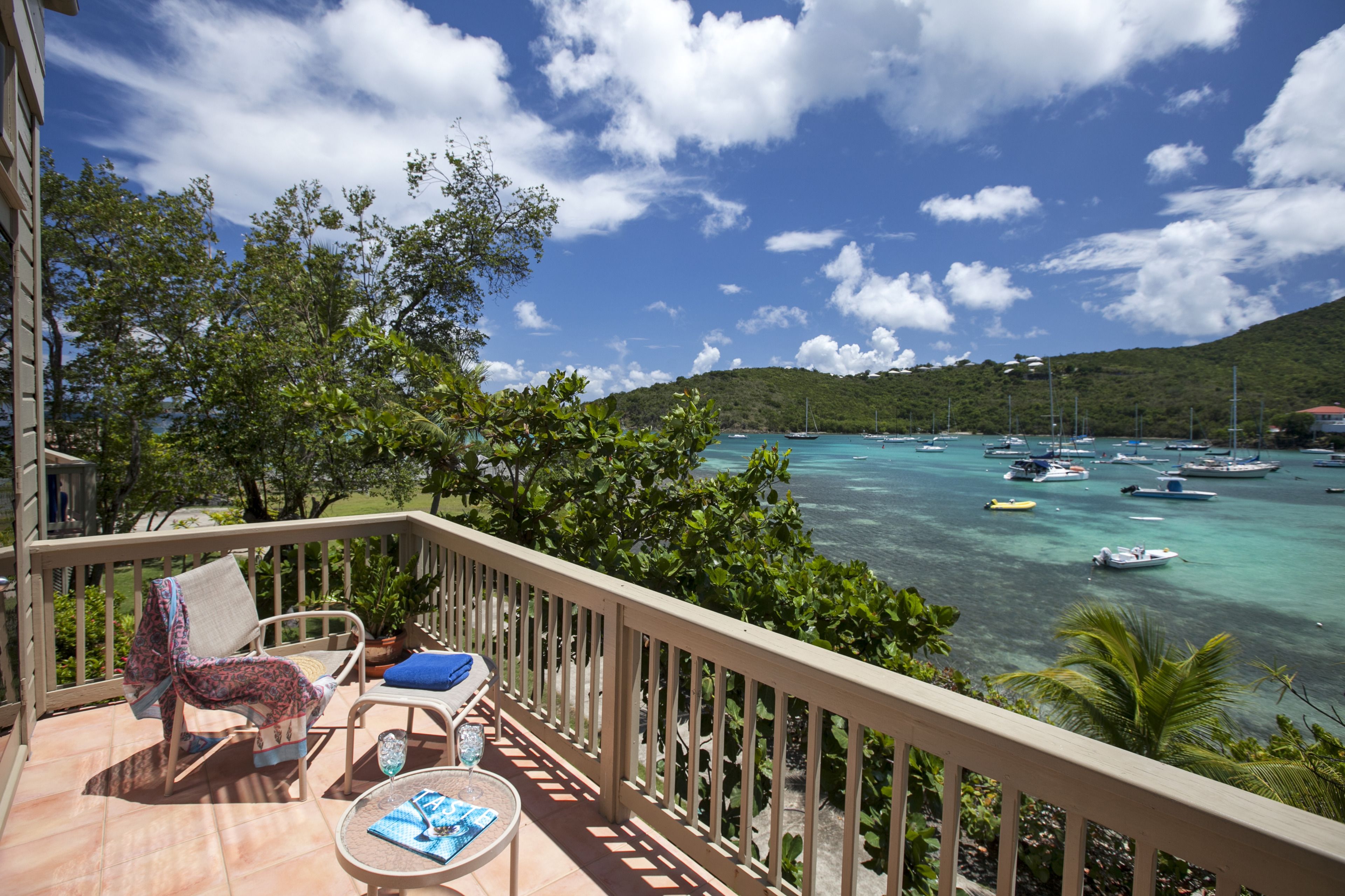 A balcony with a view of the sea, a chair, a table, and a potted plant.