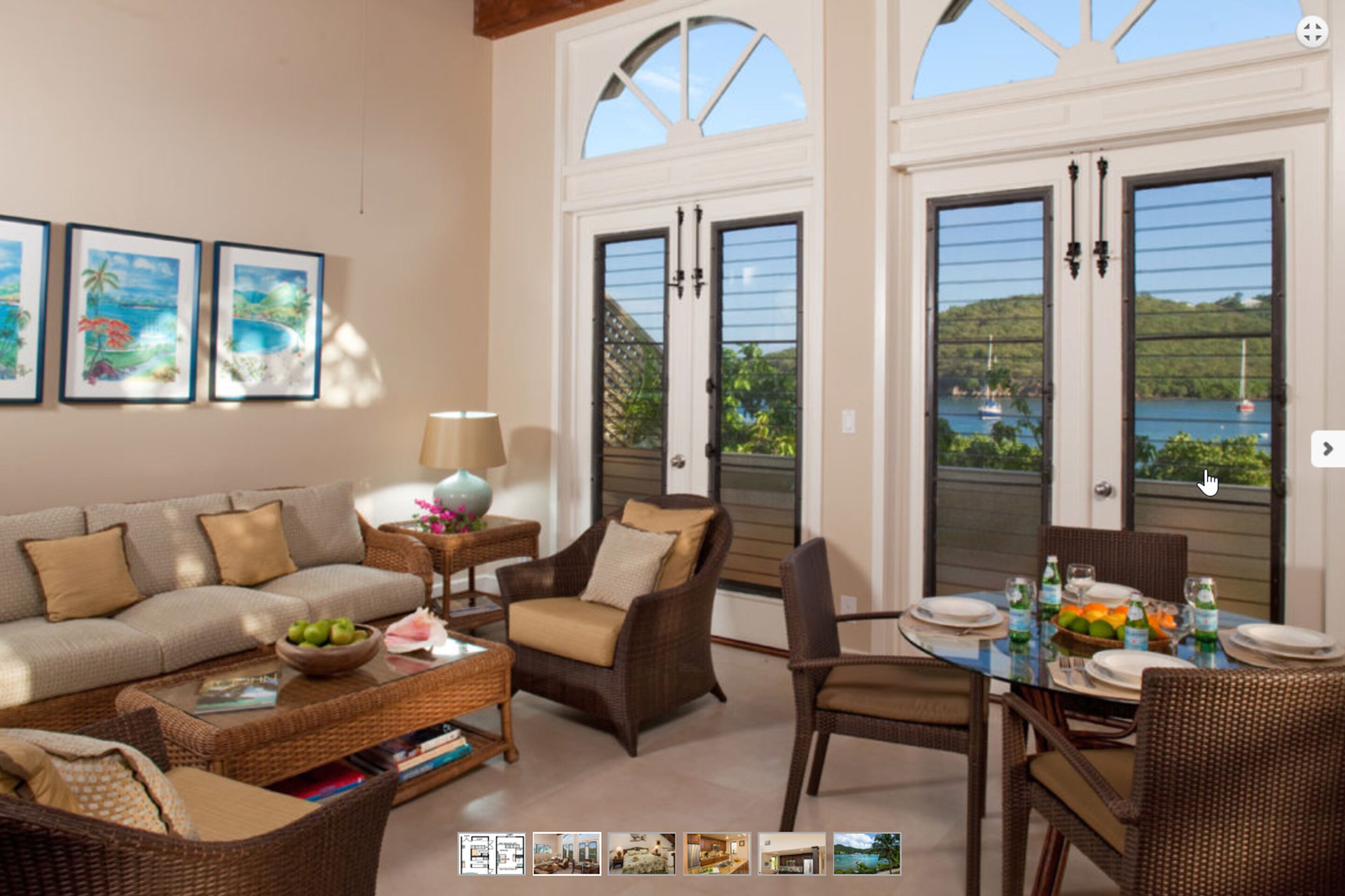 A spacious living room with a sofa, armchairs, a dining table set for four, and a view of the outdoors through large windows.