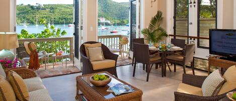 A spacious living area with a view of the water, furnished with sofas, chairs, and a dining table.
