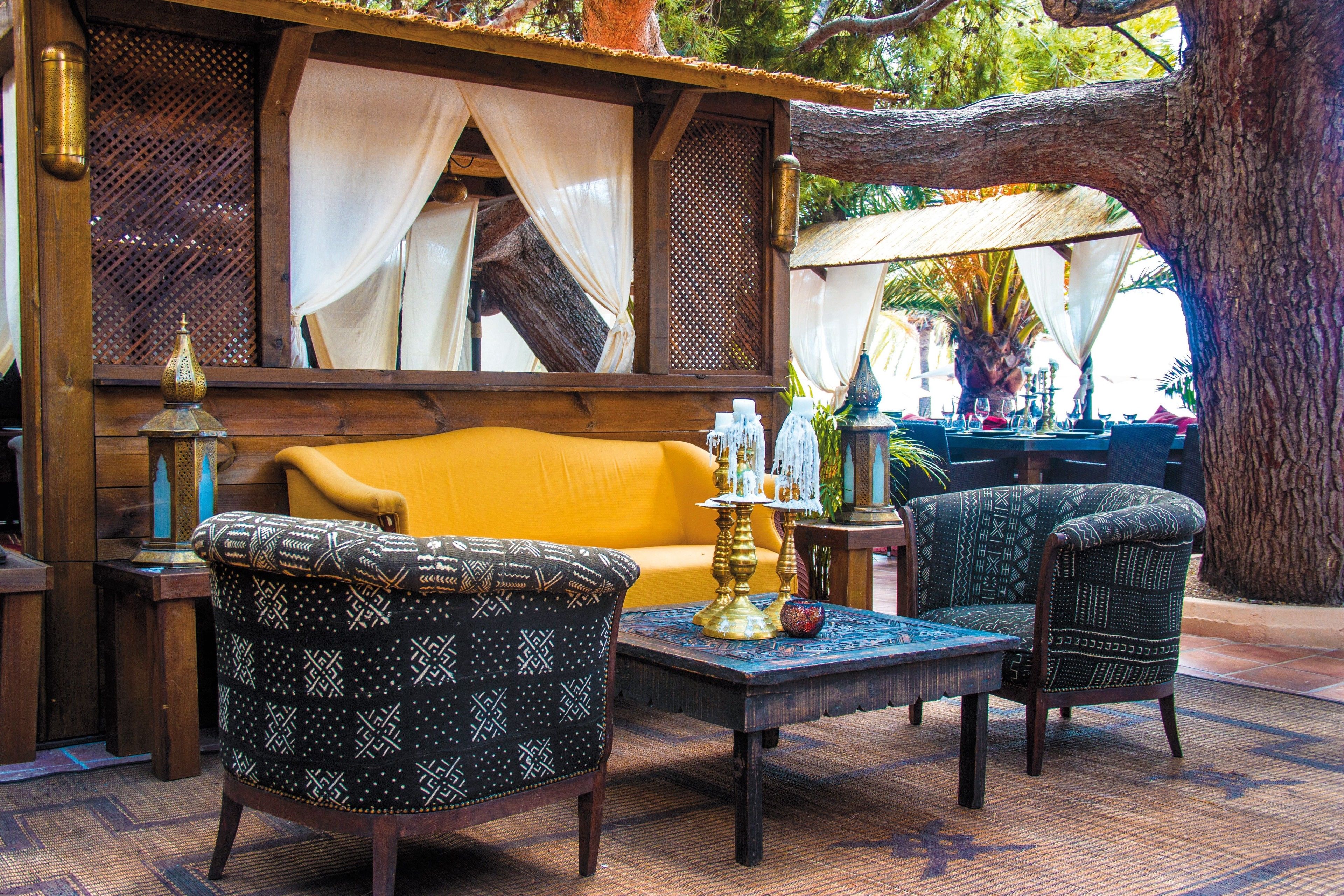 A cozy outdoor seating area with patterned furniture, a yellow sofa, and a decorative table.