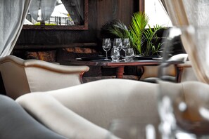 Comedor con una mesa preparada para cuatro personas, incluyendo copas de vino y una planta en maceta.