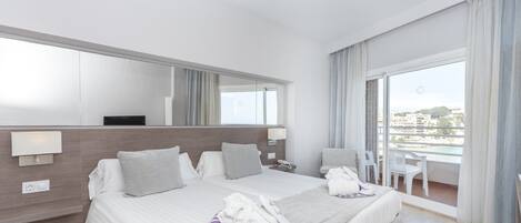 A hotel room with a large bed, a desk, a chair, and a balcony with a view.