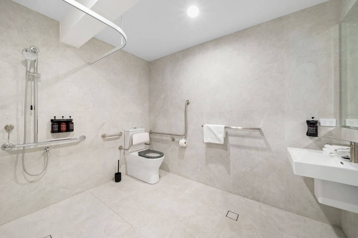 A modern bathroom with a shower, toilet, and sink.