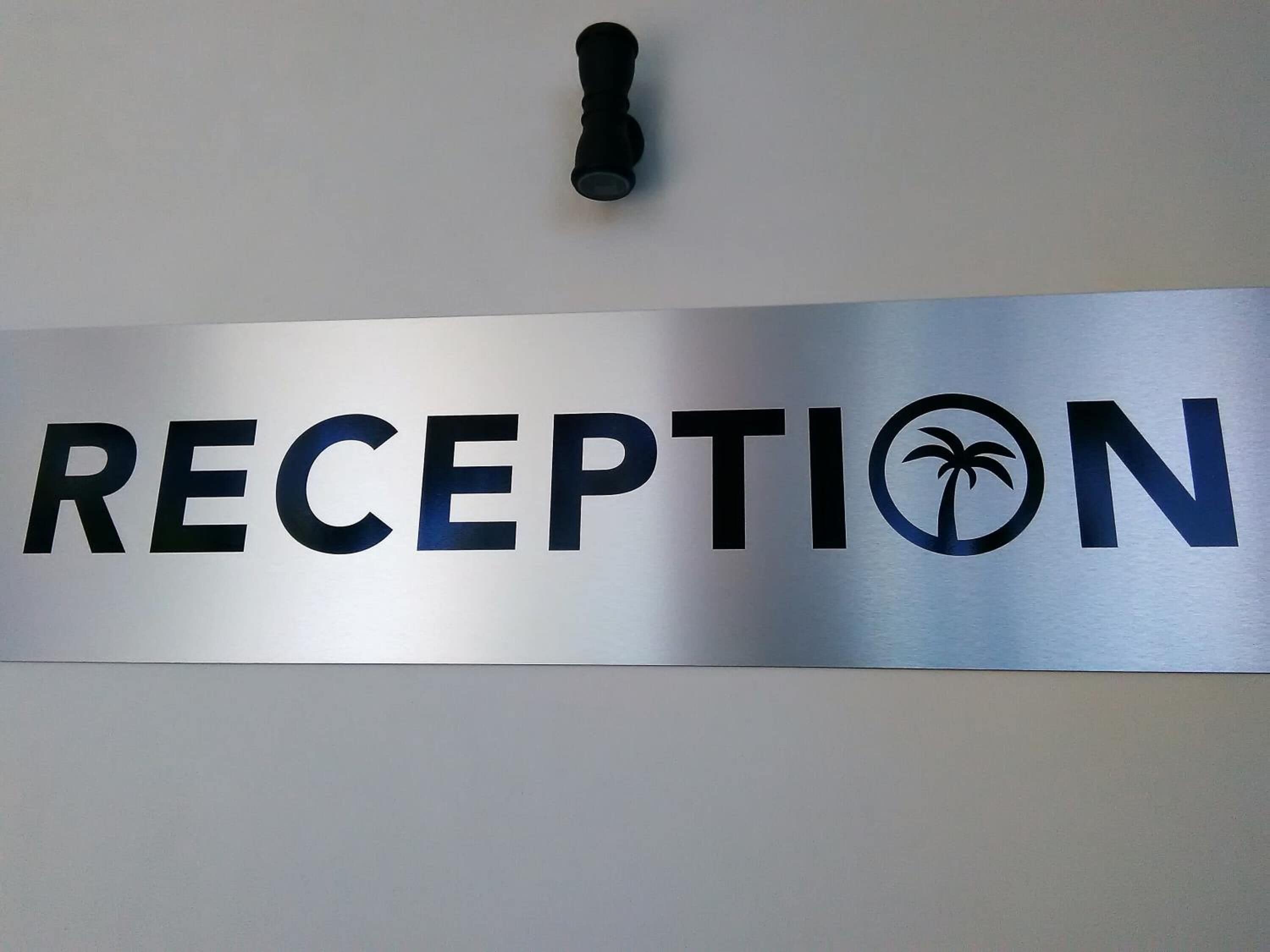 Un letrero con la palabra 'RECEPTION' y un símbolo de palmera.