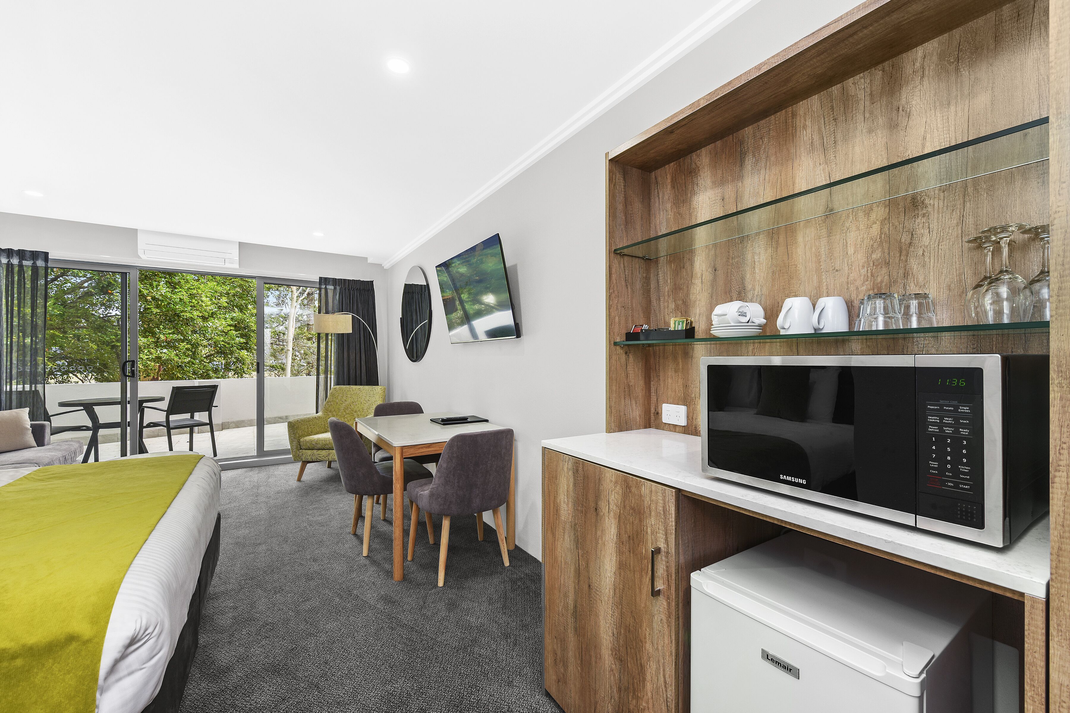 Une chambre d’hôtel moderne équipée d’un lit, d’un coin repas, d’un four à micro-ondes et d’un réfrigérateur.