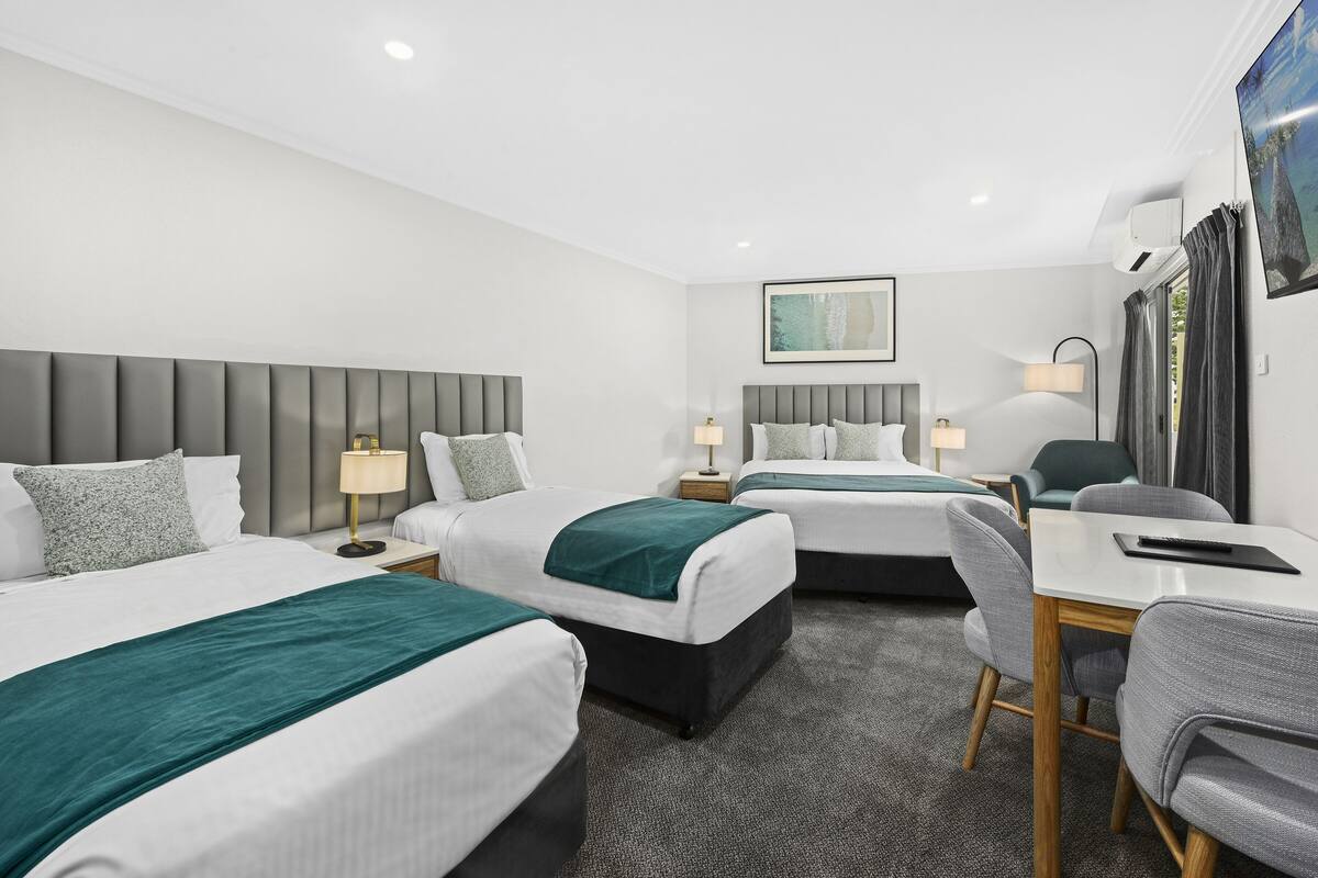 A hotel room with two beds, a desk, and a chair.