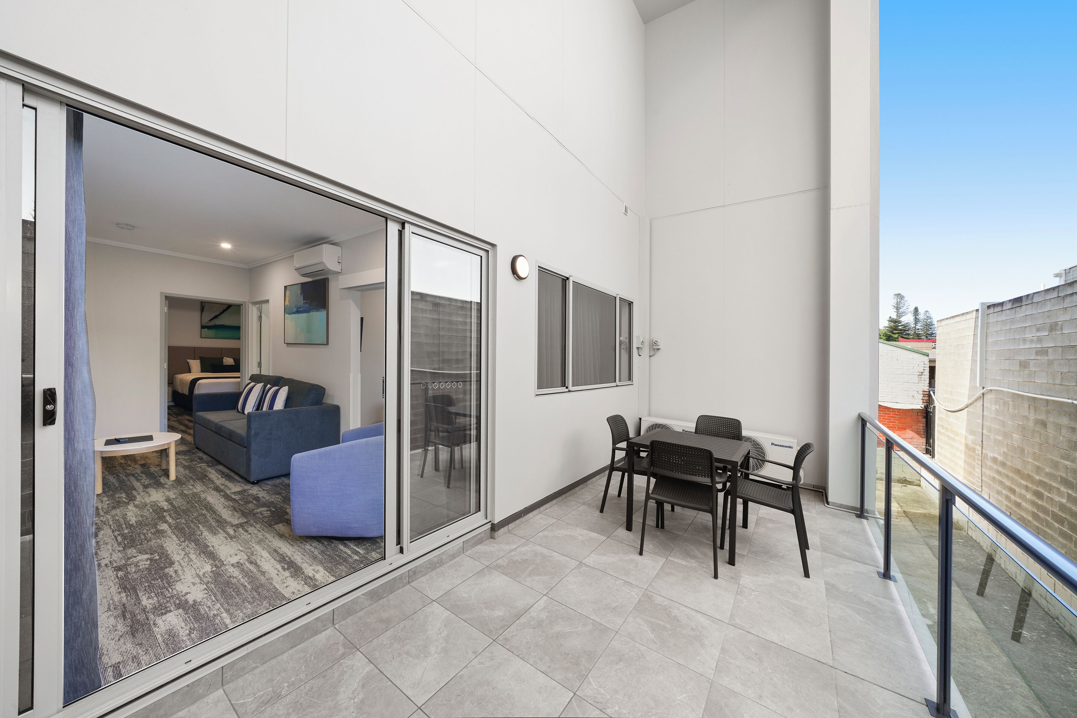 A modern apartment with a balcony, a dining area, and a living room with a sofa and a coffee table.