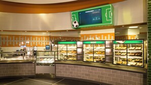 A bakery counter with glass display cases, a sports-themed wall, and a tiled backsplash. - Disney's All Star Sports Resort (Lake Buena Vista)
