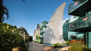 A pathway leading to uniquely shaped buildings with balconies, surrounded by greenery and palm trees. - Disney's All Star Sports Resort (Lake Buena Vista)