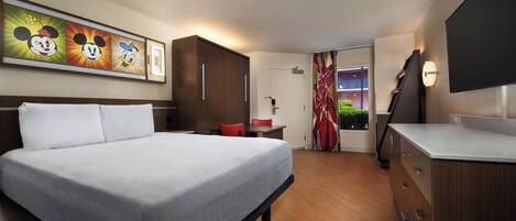 Quarto de hotel com uma cama grande, uma escrivaninha, uma cadeira, um armário e uma televisão.