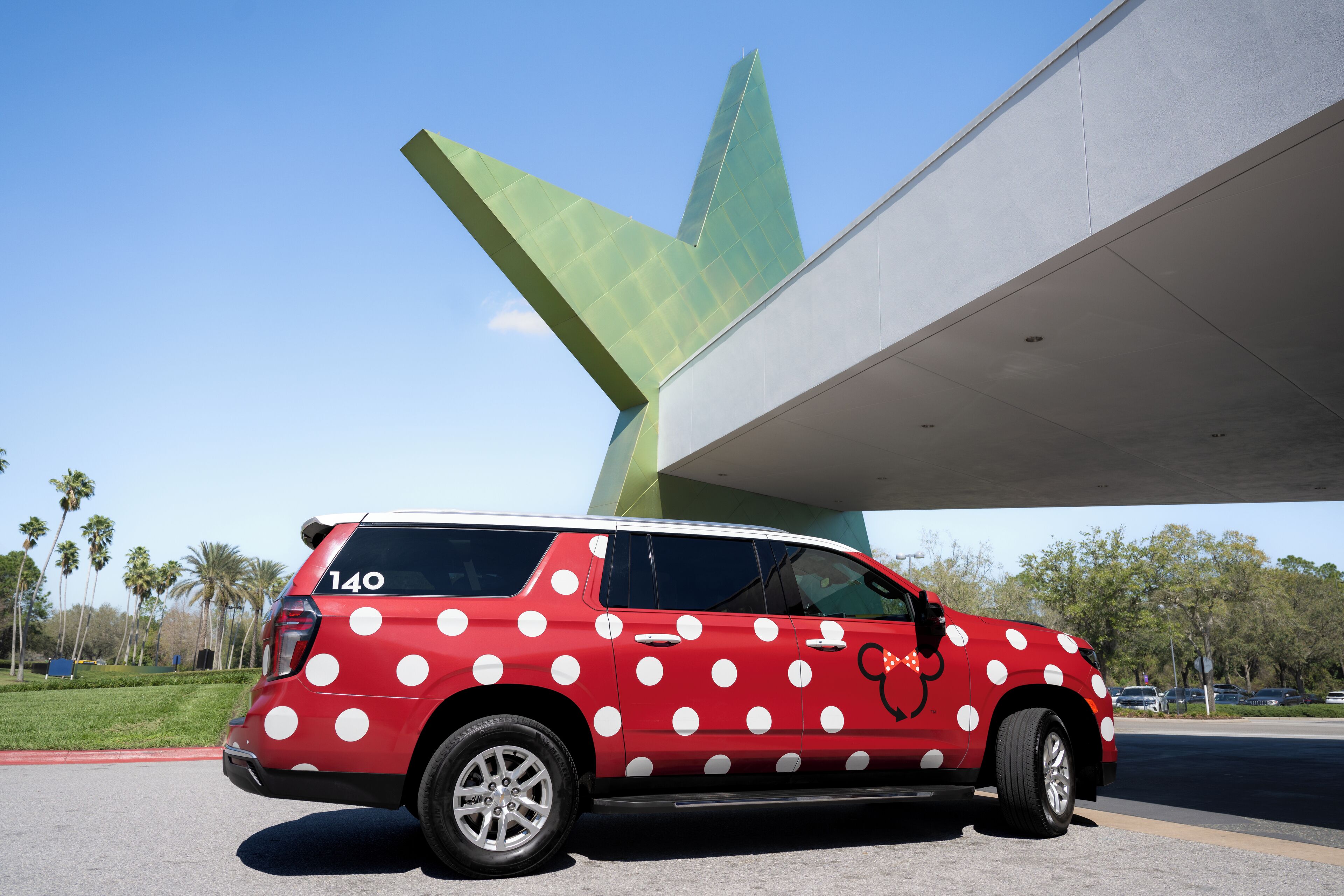 Un véhicule rouge à pois blancs est garé sous une structure moderne.