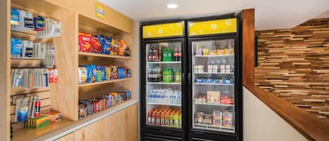 A corner of a store with shelves stocked with snacks and beverages, and two refrigerators.
