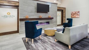 Un moderno vestíbulo de hotel con una televisión de pantalla plana, chimenea y asientos cómodos.