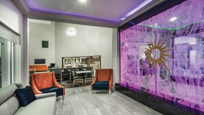 Un interior moderno con mostrador de recepción, zona de estar y una pared decorativa con un motivo de sol.