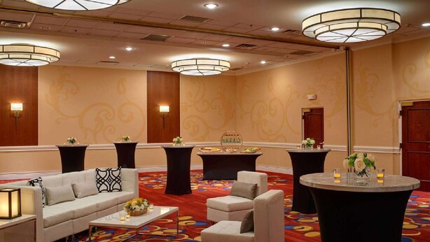 A hotel lobby with a sofa, armchairs, a coffee table, a buffet table, and a round table with flowers.