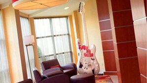 A hotel lobby with dark leather sofas, a colorful patterned carpet, and a large guitar sculpture.