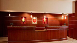 A reception desk with a wooden finish, two wall-mounted light fixtures, and a small plant on the counter.