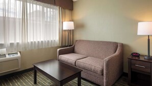 A hotel room with a sofa, a small table, a lamp, and a heater. - Best Western Holiday Hotel (Coos Bay)