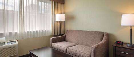 Une chambre d’hôtel avec un canapé, une petite table, une lampe et un radiateur.
