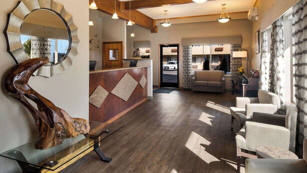 A hotel lobby with a reception desk, seating area, and a large mirror. - Best Western Holiday Hotel (Coos Bay)