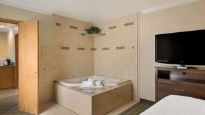 A modern hotel room with a large bathtub, a flat-screen TV, and a wooden cabinet. - Best Western Holiday Hotel (Coos Bay)