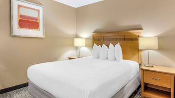 Habitación de hotel con una cama grande, dos lámparas de noche, un cabecero de madera y una obra de arte enmarcada en la pared.