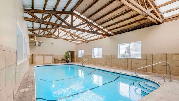 Una piscina interior amb terra de rajola, estructura de sostre de fusta i una finestra que deixa entrar llum natural.