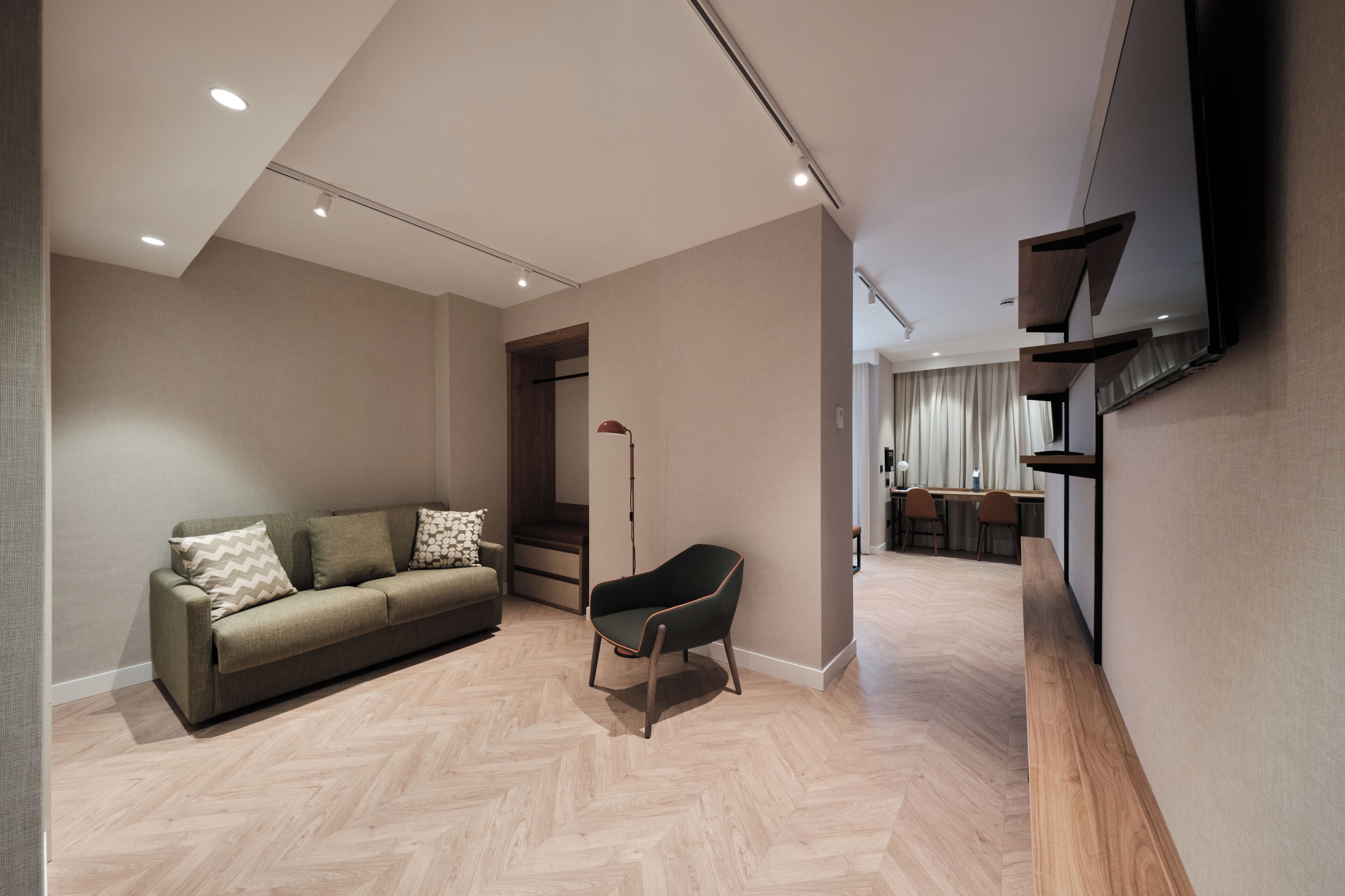 Een moderne woonkamer met een bank, een fauteuil en een eethoek op de achtergrond.