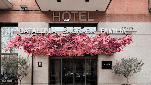 The entrance of the Catalonia Sagrada Familia Hotel with a large sign above the doors and two potted plants on either side. - Catalonia Sagrada Familia (Barcelona)