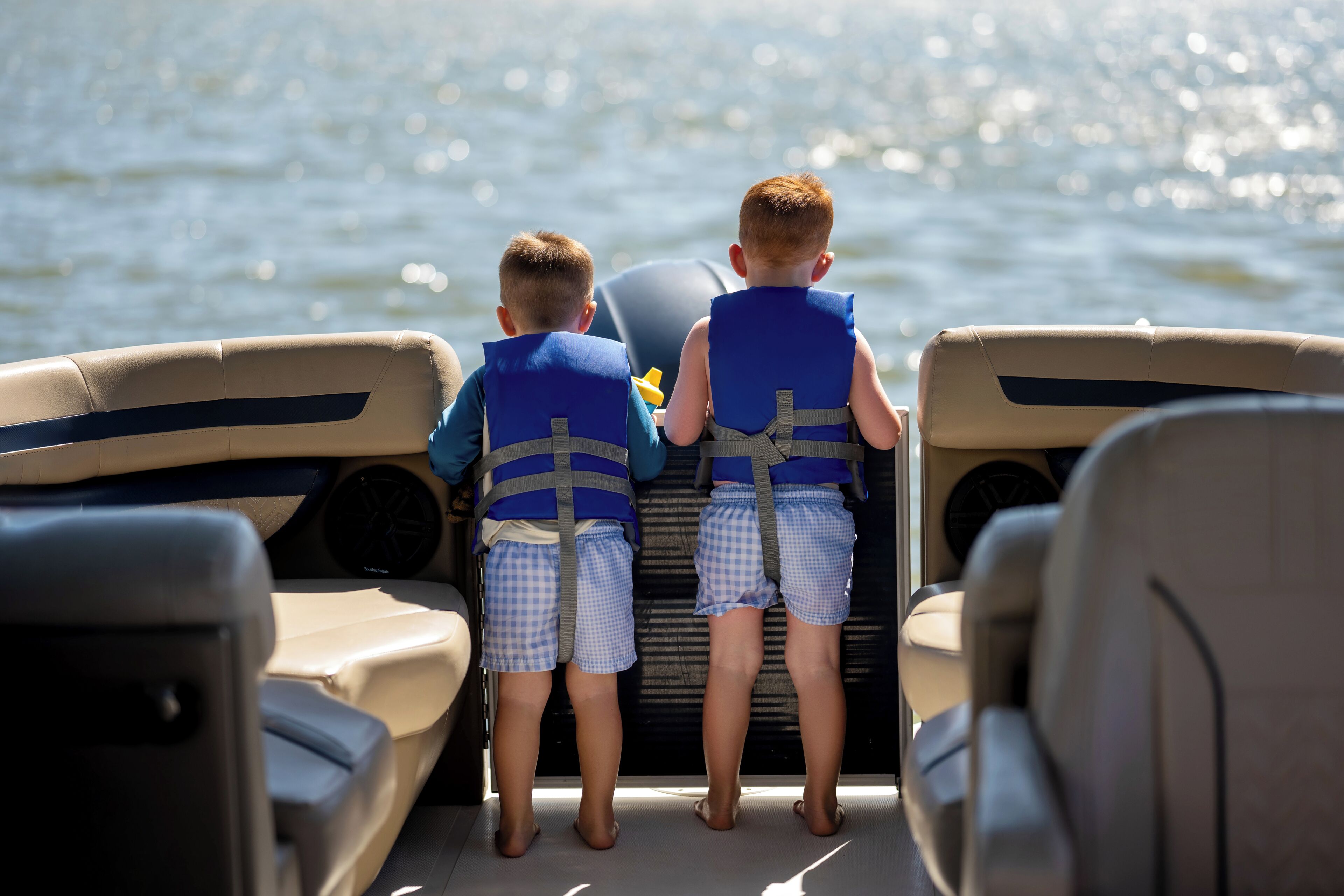 Two children on a boat wearing life jackets.