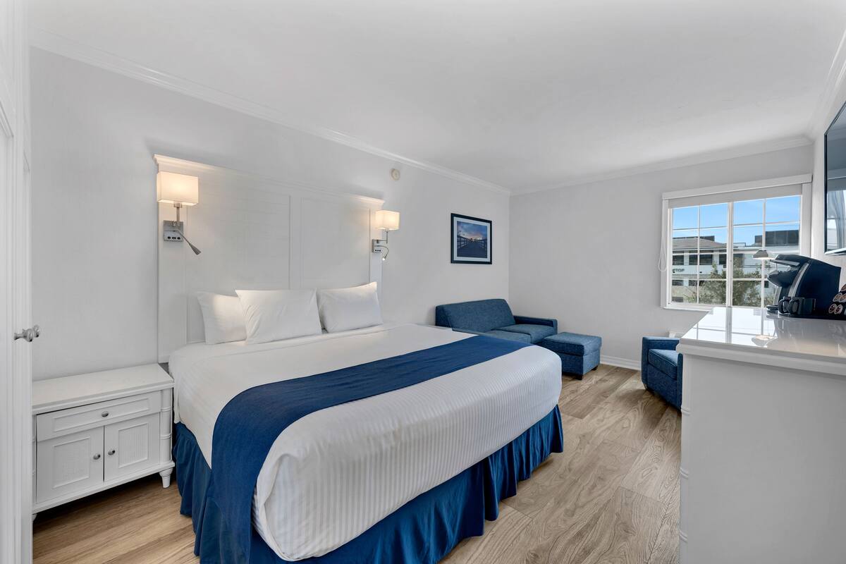 A hotel room with a large bed, a desk, and a view of the outside.
