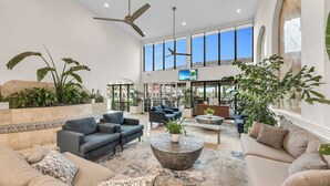 A spacious lobby with a high ceiling, large windows, and a variety of seating arrangements including sofas and armchairs. - Bayfront Inn Fifth Avenue (Naples)