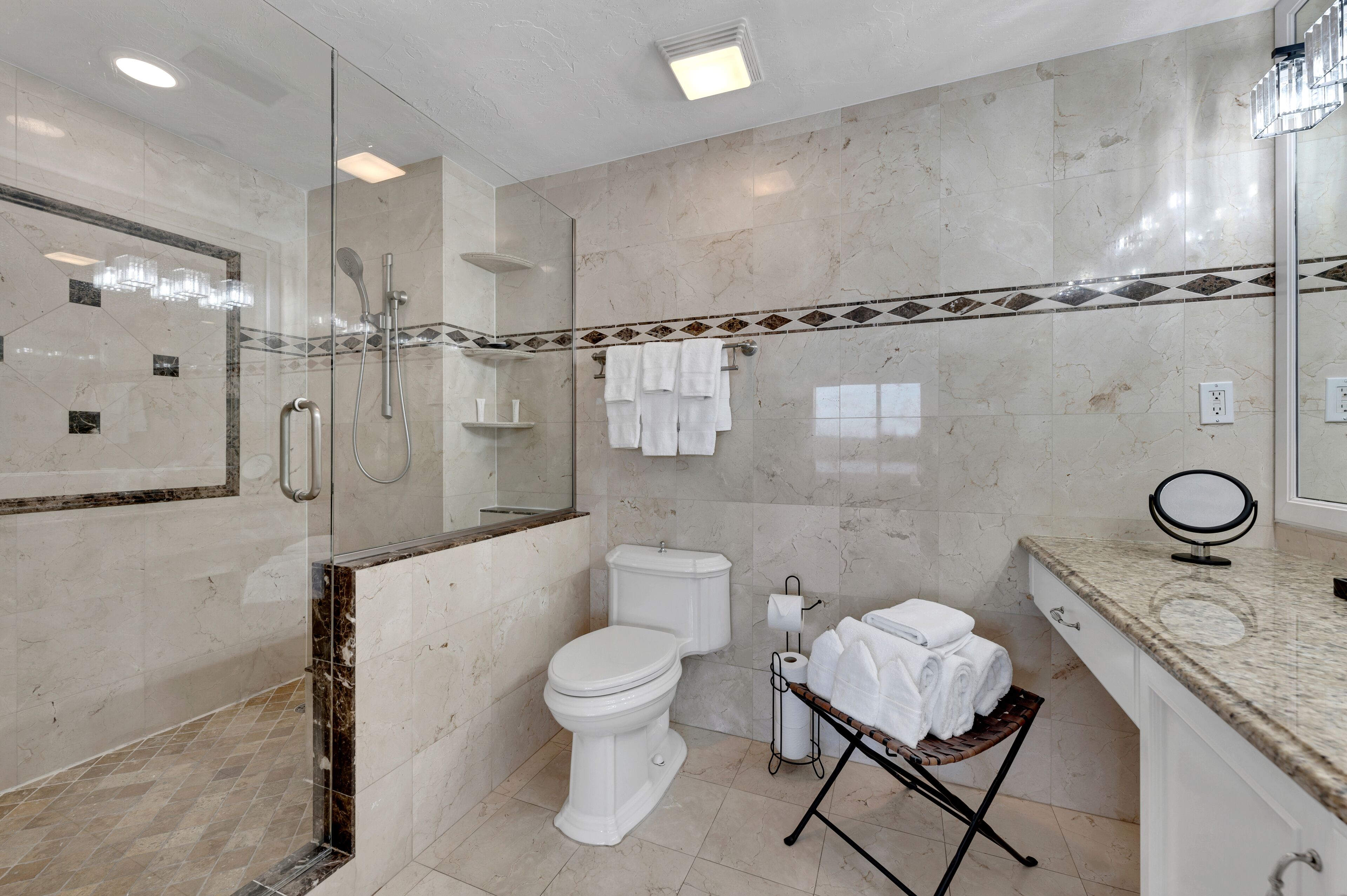 Un bagno moderno con doccia vetrata, un water, un lavandino con mobile contenitore e uno specchio.
