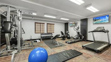 A gym with various exercise equipment, a blue exercise ball, and a treadmill.