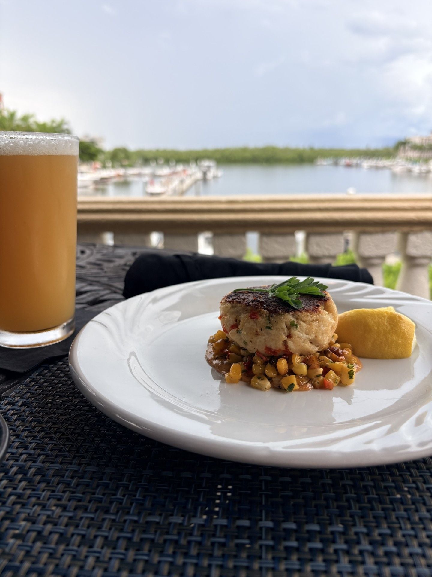 A meal on a white plate with a view of a body of water and boats in the background.