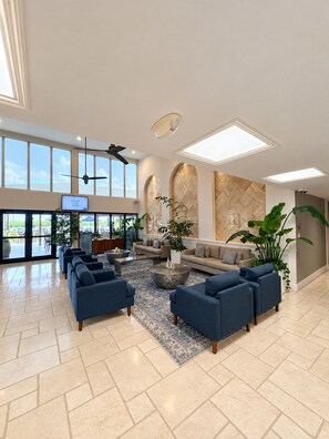 Eine geräumige Lobby mit einer Sitzecke, großen Fenstern und einem Fernsehbildschirm.