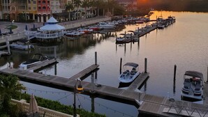 A marina with boats docked, a waterfront promenade with outdoor seating, and multi-story buildings in the background. - Bayfront Inn Fifth Avenue (Naples)