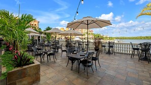 An outdoor patio with tables and chairs, umbrellas, and potted plants. - Bayfront Inn Fifth Avenue (Naples)