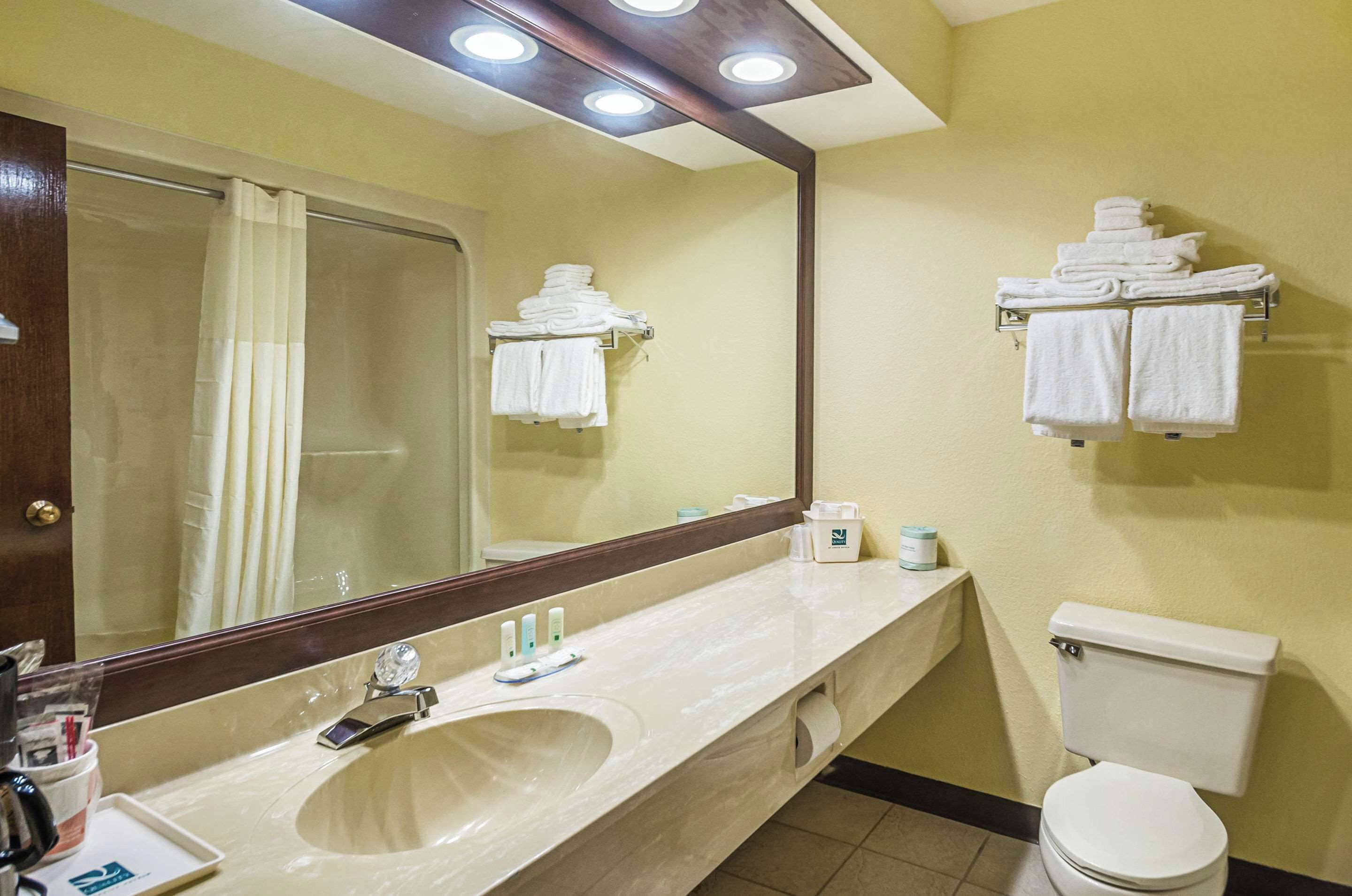 A bathroom with a sink, mirror, towel rack, and toilet.