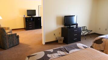 A hotel room with a bed, a TV on a dresser, a chair, and a microwave.