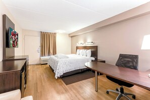 A hotel room with a bed, a desk, a chair, a TV, and a window with curtains. - Red Roof Inn PLUS+ Mt Pleasant - Patriots Point (Mount Pleasant)