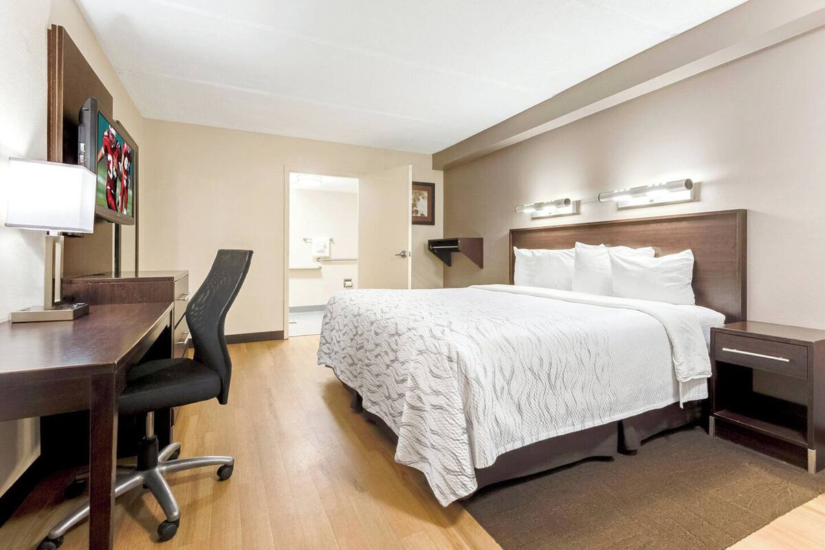A hotel room with a bed, desk, chair, and bedside lamps.