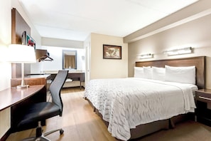 A hotel room with a bed, desk, chair, and a mirror. - Red Roof Inn PLUS+ Mt Pleasant - Patriots Point (Mount Pleasant)