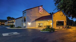 A Red Roof Plus hotel with a modern design, featuring a prominent neon sign, a covered entrance, and landscaped areas. - Red Roof Inn PLUS+ Mt Pleasant - Patriots Point (Mount Pleasant)