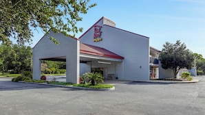 A Red Roof Plus hotel with a single-story structure, a covered entrance, and a parking lot.