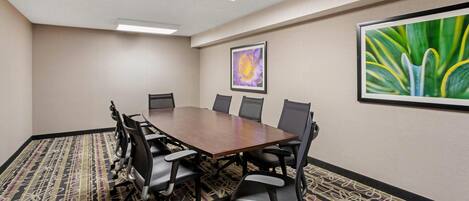A conference room with a long table, multiple chairs, and two framed floral paintings on the walls.