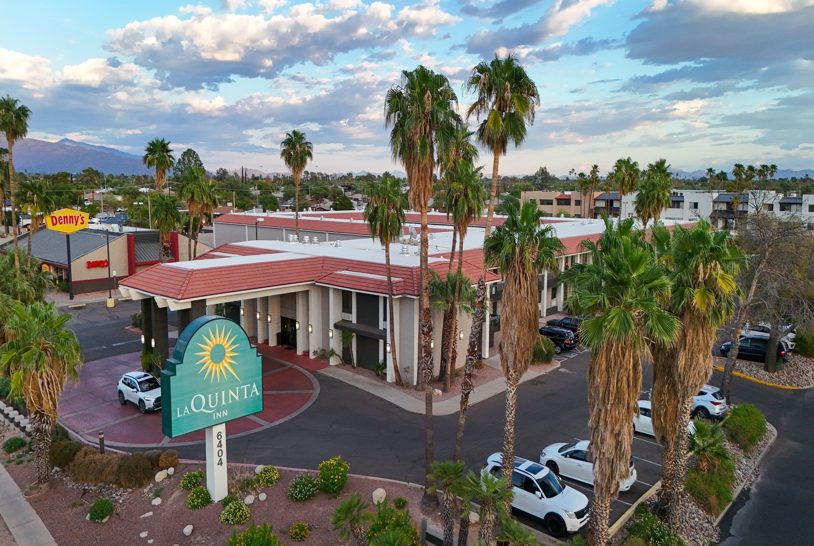 A hotel with a red roof, palm trees, and a sign for 'La Quinta Inn'.