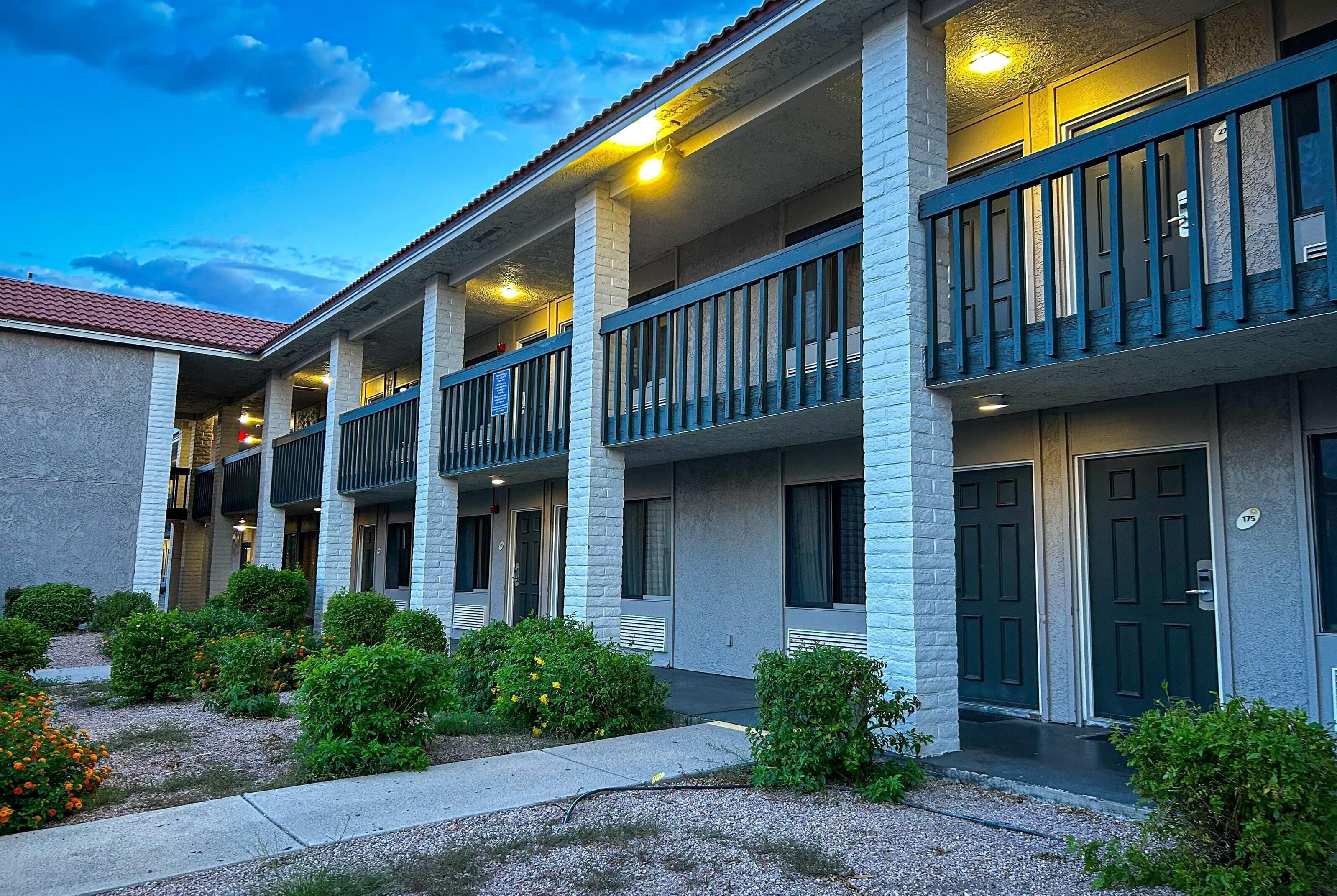 A multi-story hotel with balconies, a covered walkway, and a landscaped entrance.