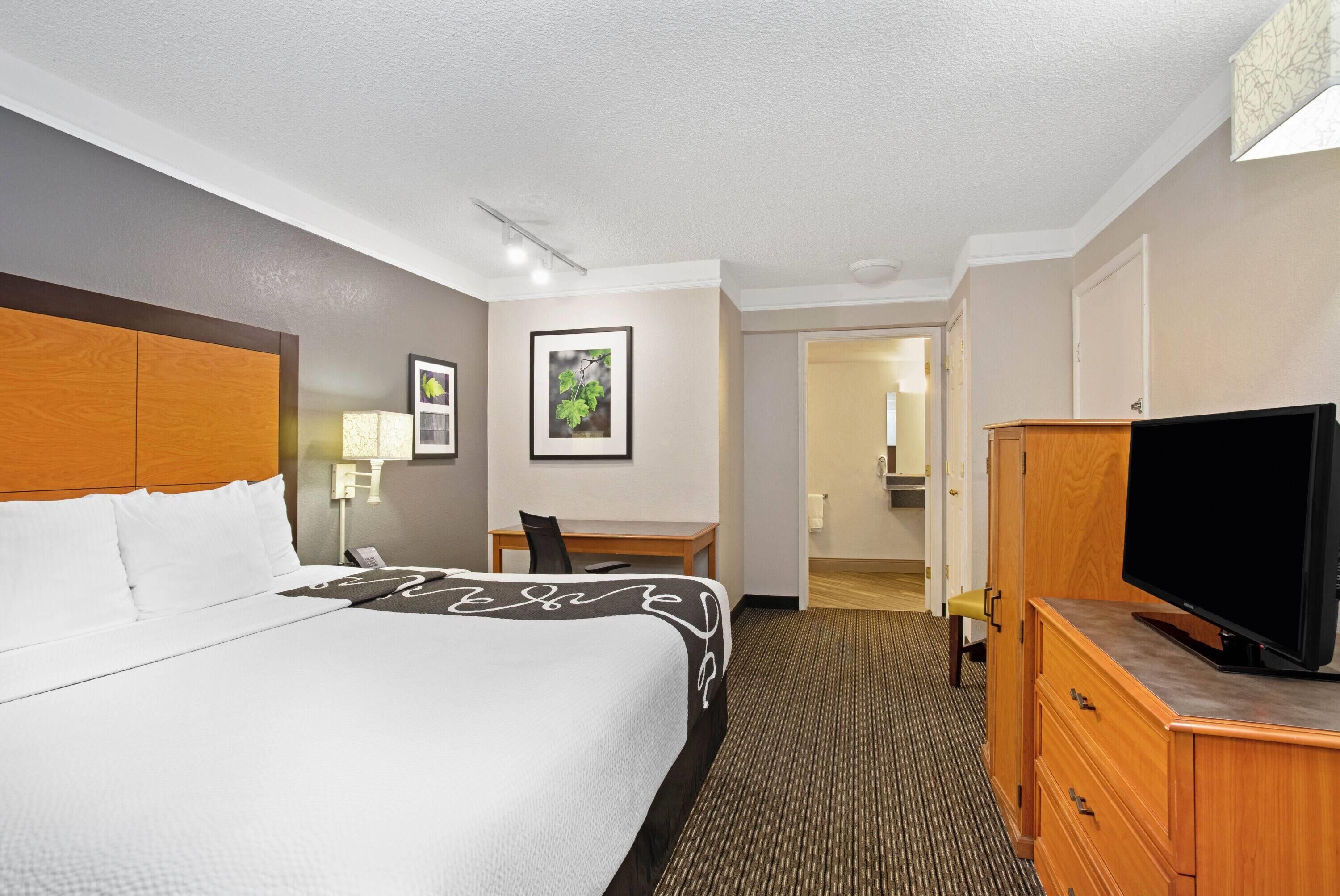 A hotel room with a bed, a desk, a television, and a wardrobe.